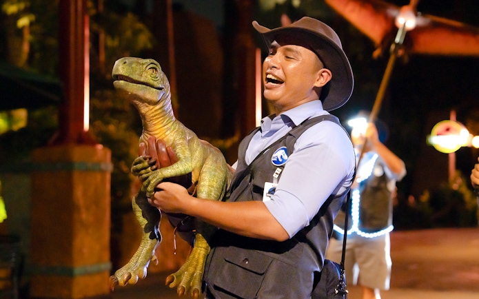 Man holding a dinosaur puppet at Universal Studios Singapore.