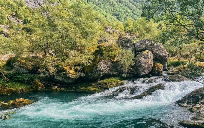 Folgefonna National Park glacier lake with flowing water and surrounding lush greenery.