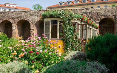 Historic tram surrounded by flowers at QC Terme spa garden in Milan.
