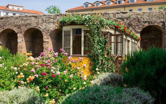 Historic tram surrounded by flowers at QC Terme spa garden in Milan.