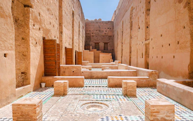 Courtyard ruins of El Badi Palace with mosaic tiles and ancient walls in Marrakech, Morocco.