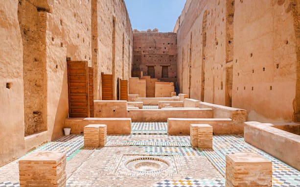 Courtyard ruins of El Badi Palace with mosaic tiles and ancient walls in Marrakech, Morocco.