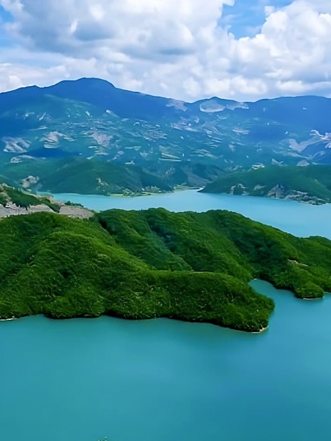 Bovilla Lake surrounded by lush green hills and distant mountains.