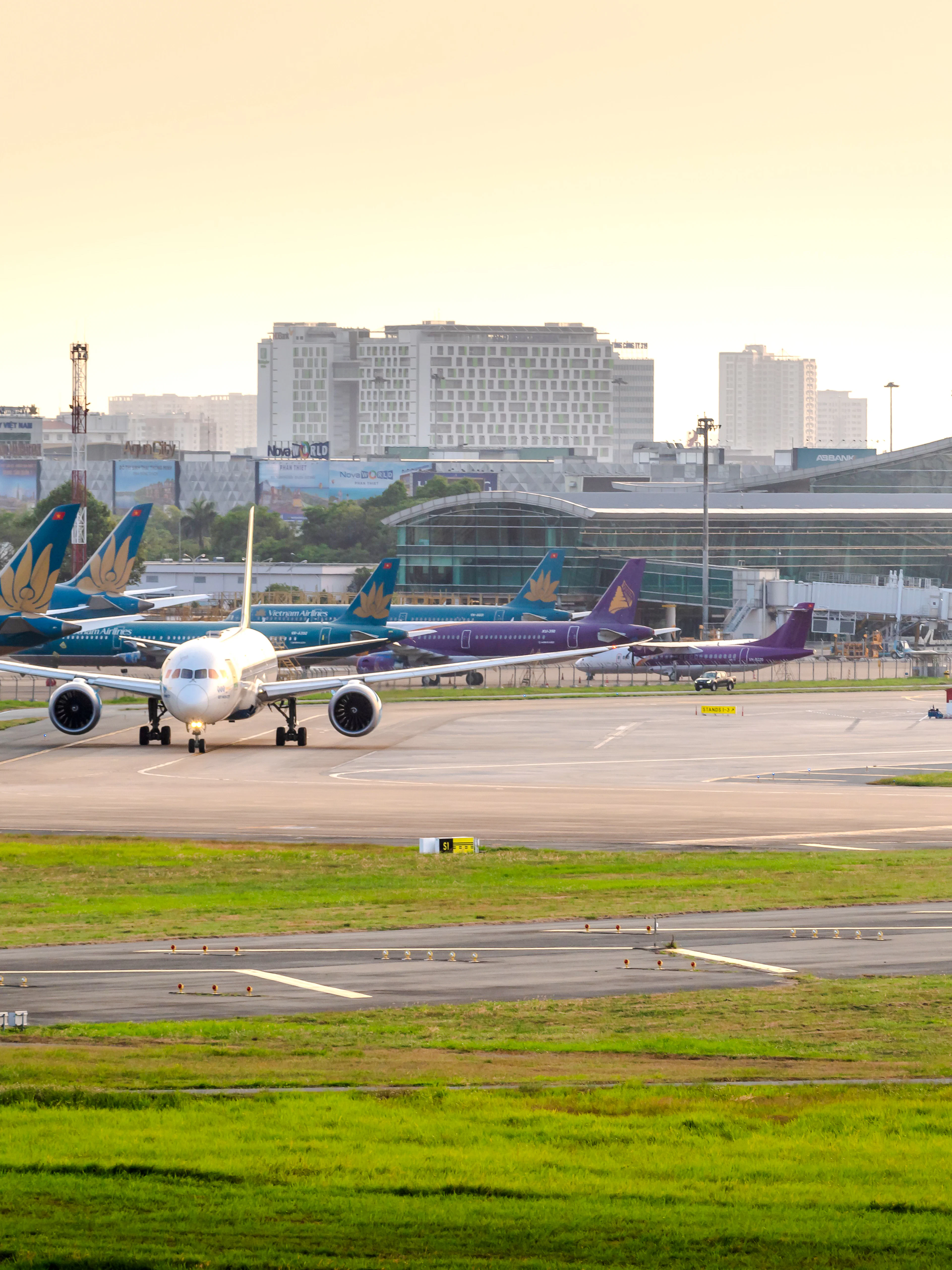 Airplanes at Noi Bai International Airport in Hanoi, Vietnam, with terminal in the background.