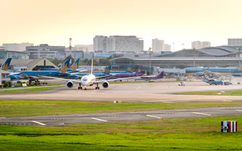 Airplanes at Noi Bai International Airport in Hanoi, Vietnam, with terminal in the background.