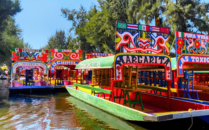 Colorful trajineras on a canal during a Xochimilco tour in Mexico City.