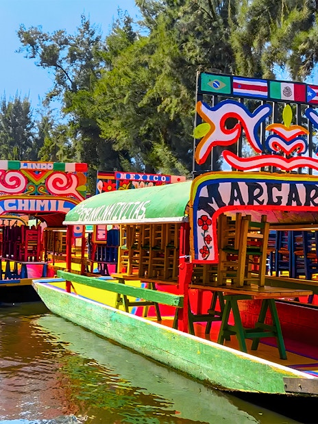 Colorful trajineras on a canal during a Xochimilco tour in Mexico City.