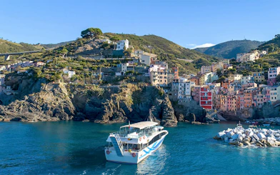 Cruise ship approaching colorful cliffside village in Cinque Terre, Italy.