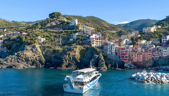 Cruise ship approaching colorful cliffside village in Cinque Terre, Italy.