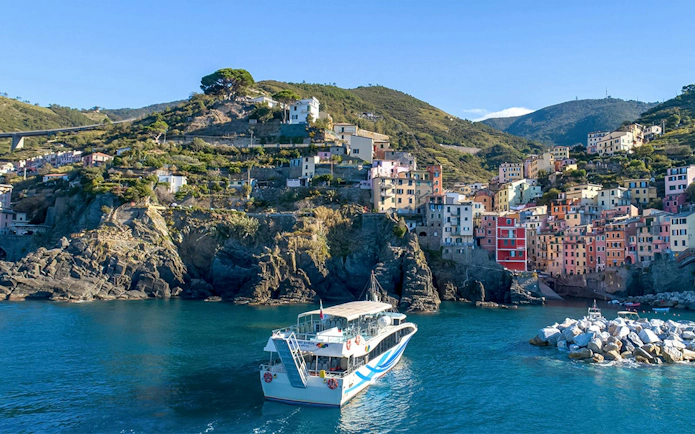 Cruise ship approaching colorful cliffside village in Cinque Terre, Italy.