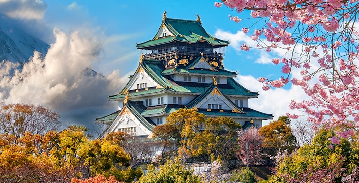 Osaka Castle surrounded by cherry blossoms with Mount Fuji in the background, Japan.