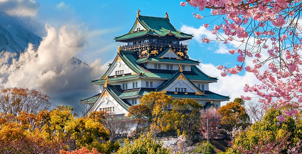 Osaka Castle surrounded by cherry blossoms with Mount Fuji in the background, Japan.