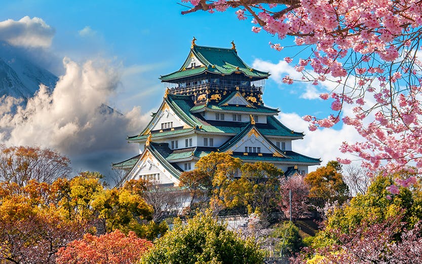 Osaka Castle surrounded by cherry blossoms with Mount Fuji in the background, Japan.