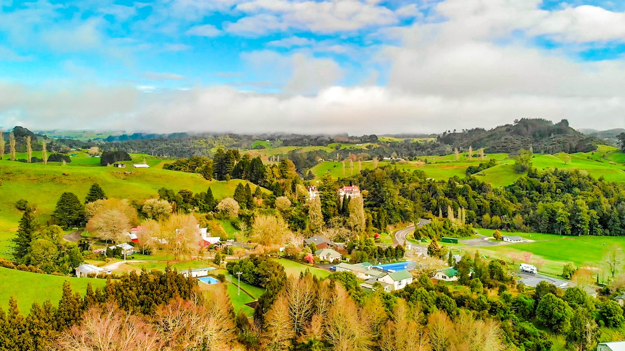 Aerial view of lush green landscape and rural homes in Waitomo, New Zealand.