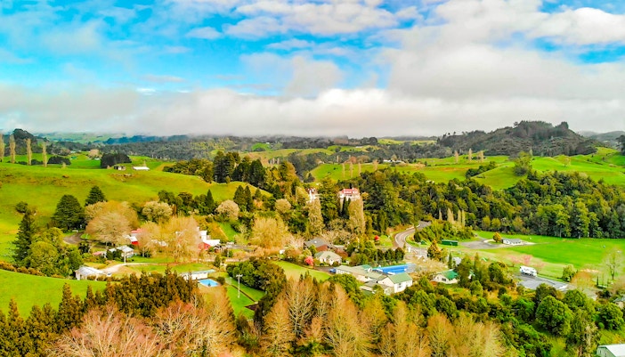 Aerial view of lush green landscape and rural homes in Waitomo, New Zealand.