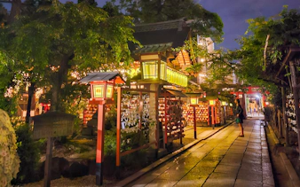 Lantern-lit path in Gion district, Kyoto, Japan, at night with traditional architecture.