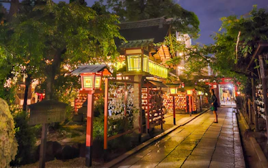 Lantern-lit path in Gion district, Kyoto, Japan, at night with traditional architecture.