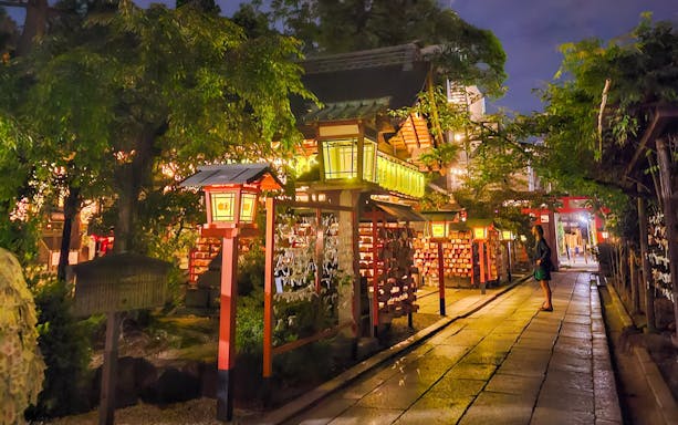 Lantern-lit path in Gion district, Kyoto, Japan, at night with traditional architecture.