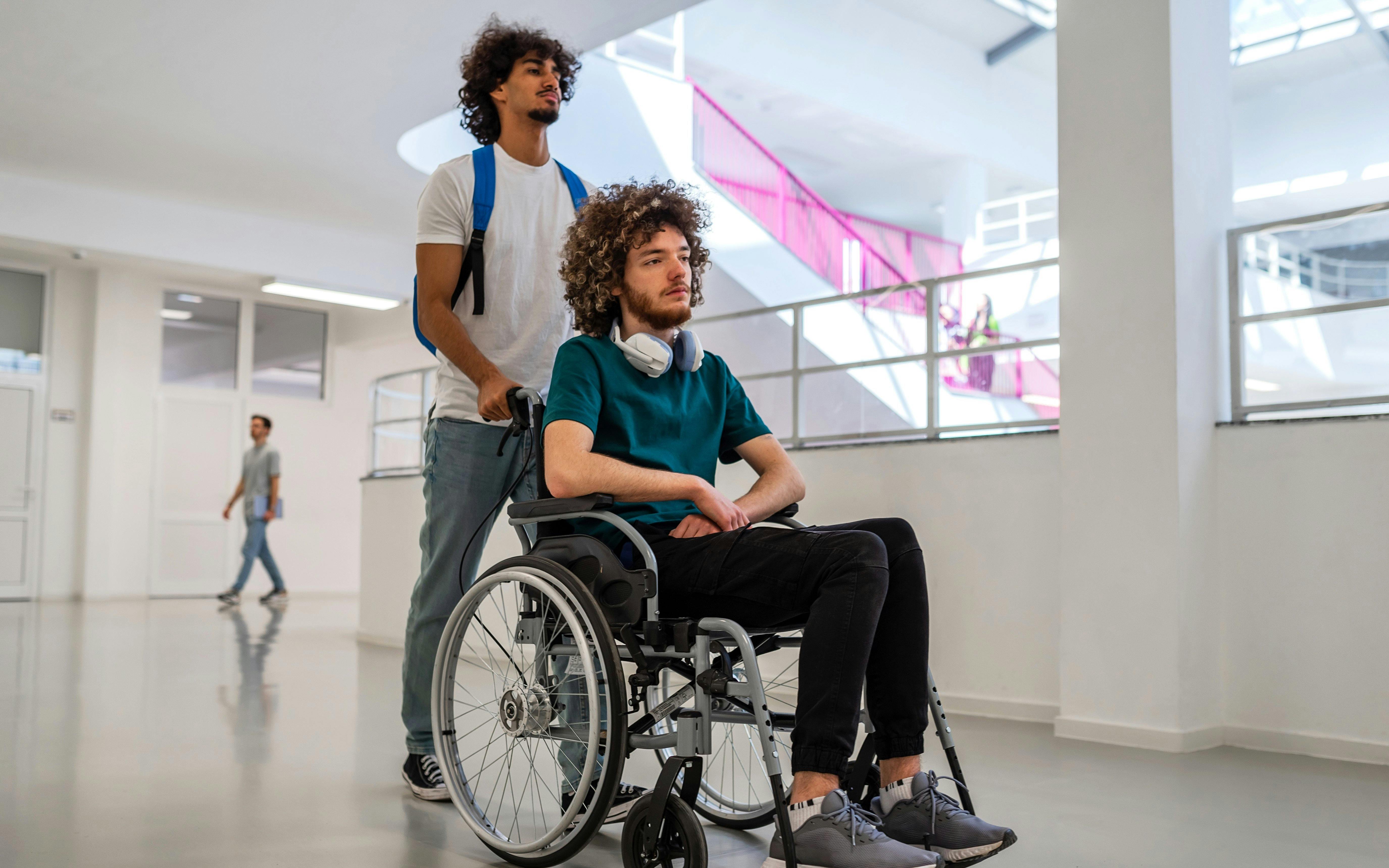 Person assisting another in a wheelchair through a bright, modern building.