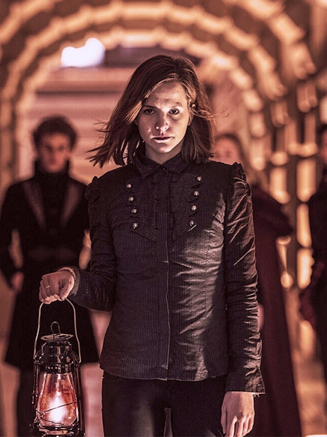 Group holding lanterns in a dimly lit archway during Budapest Buda Castle evening tour.