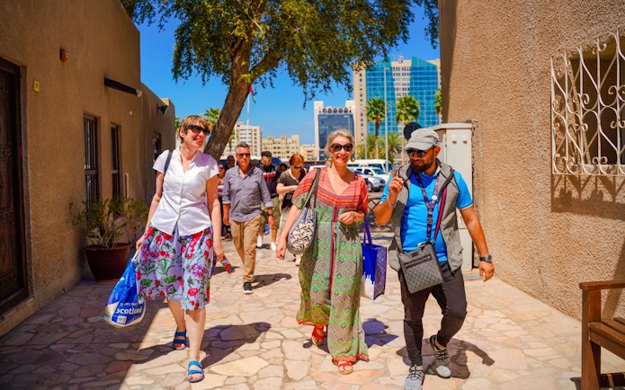 Tour guide leading tourists on a sunny street in Dubai.