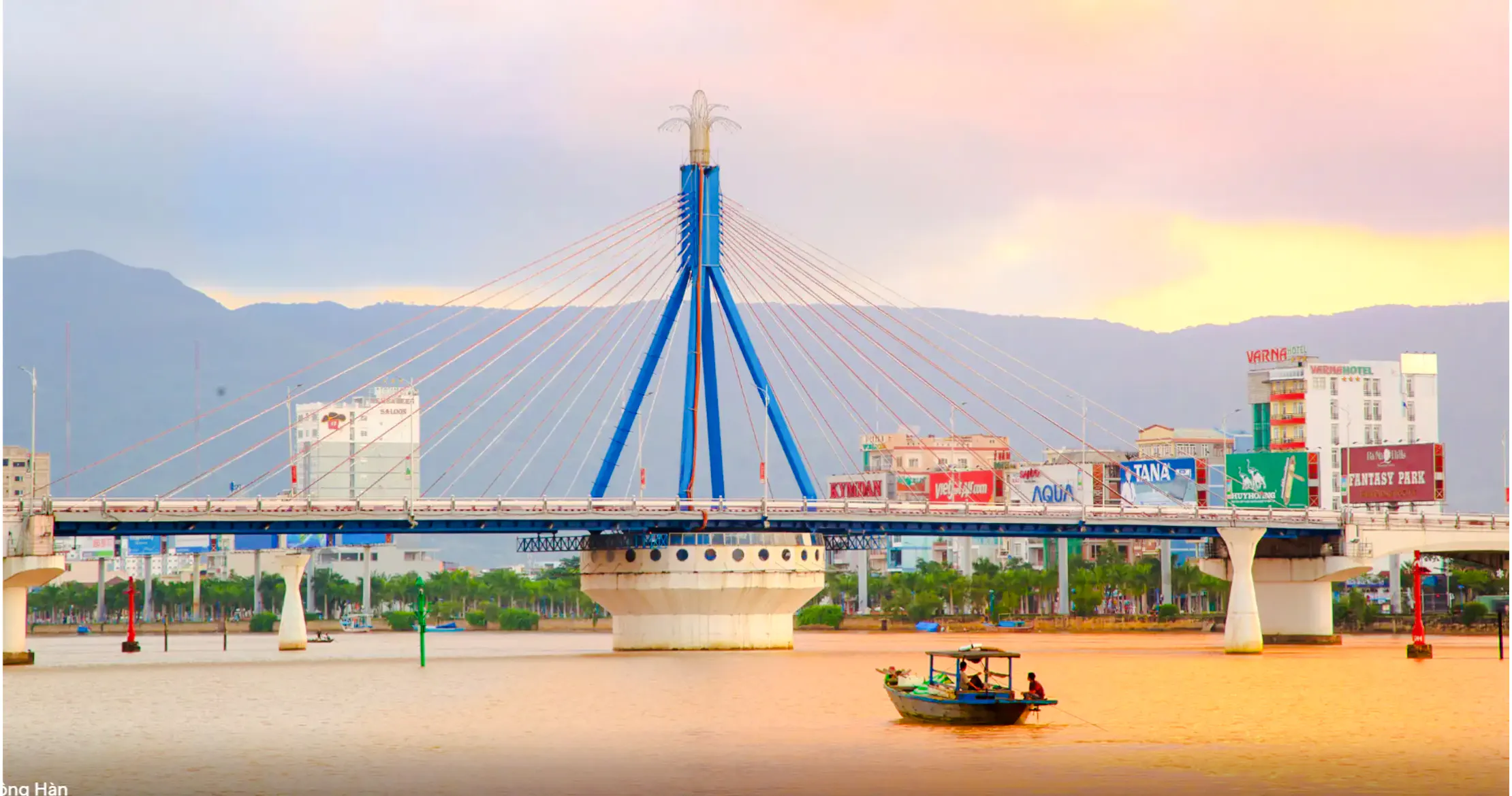 Da Nang's Han River Bridge at sunset with a boat on the water.