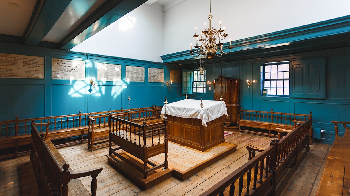 Interior of Anne Frank House with wooden benches and a chandelier, Amsterdam tour.