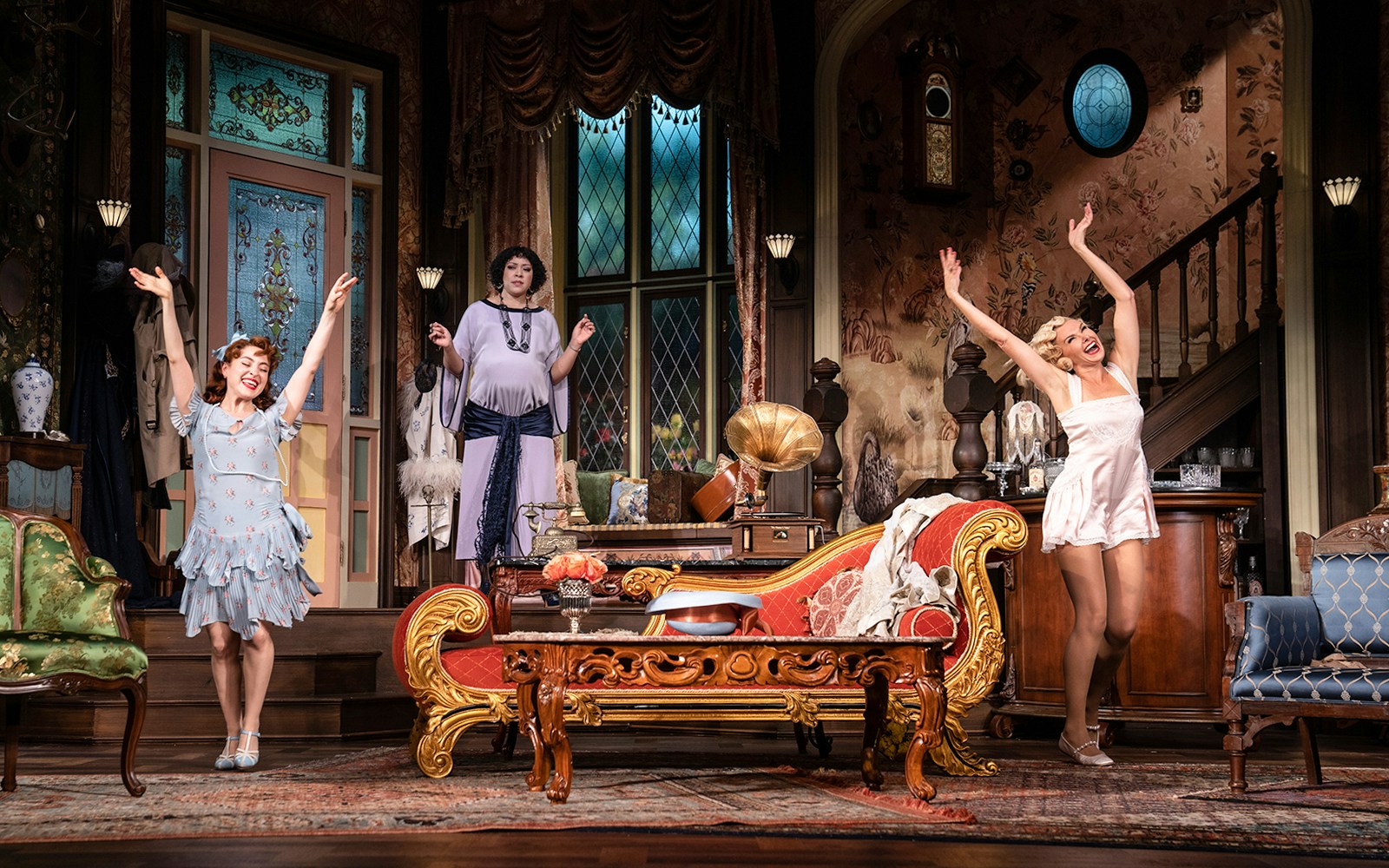 Performers on stage in a vintage living room set during "The Cottage" play.