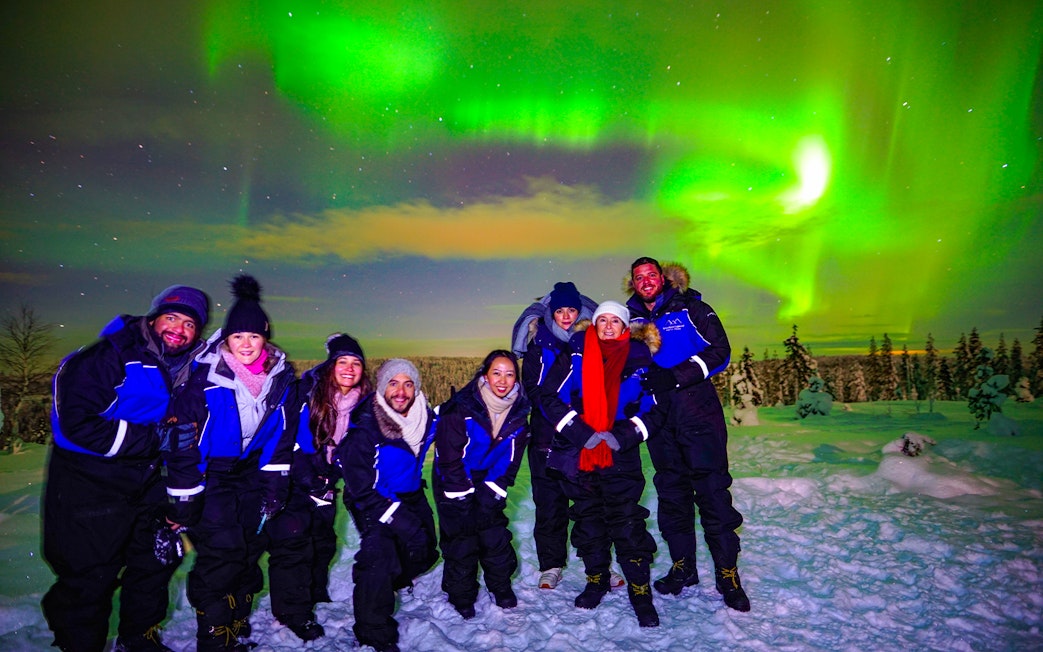 Guests enjoying the Northern Lights tour in Rovaniemi, Finland, under vibrant auroras.