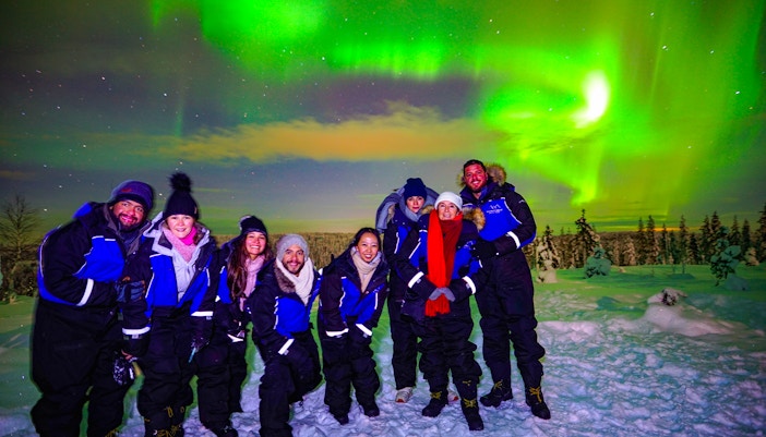Guests enjoying the Northern Lights tour in Rovaniemi, Finland, under vibrant auroras.