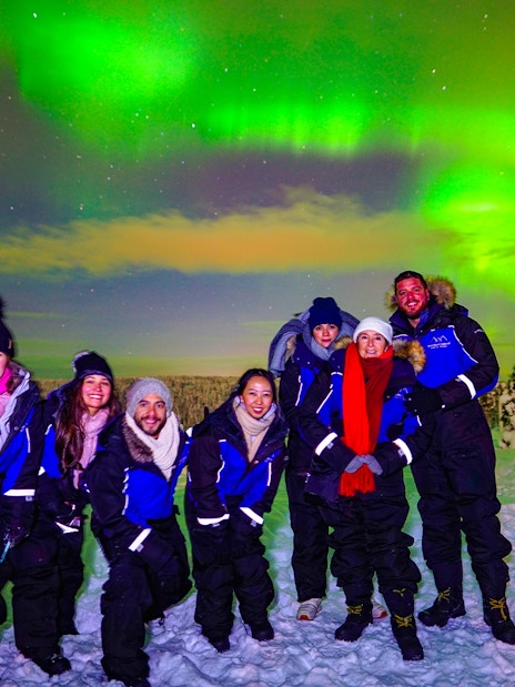 Guests enjoying the Northern Lights tour in Rovaniemi, Finland, under vibrant auroras.