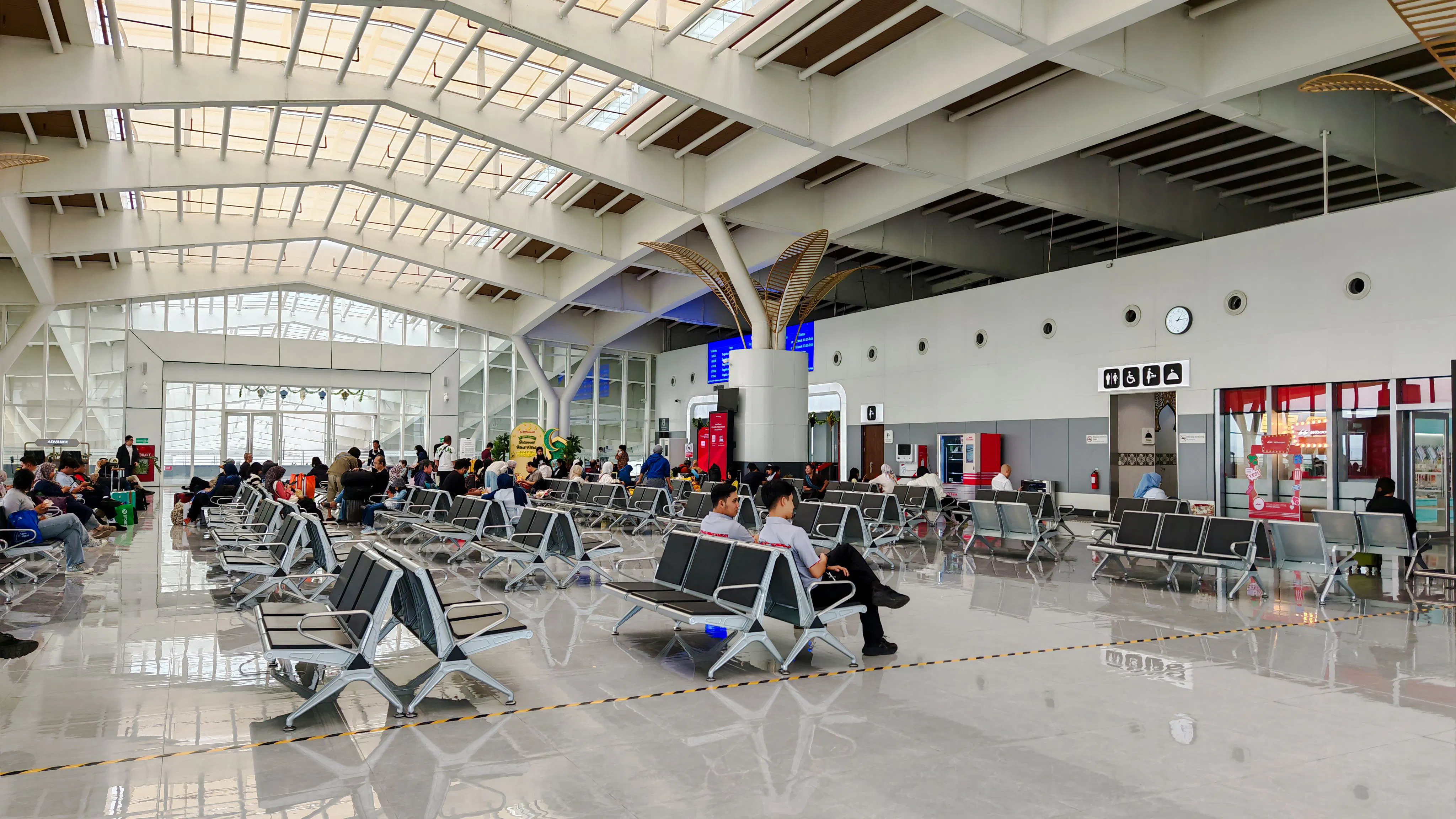 Passengers seated in Noi Bai Airport departure lounge, Hanoi, with visible signage and seating area.