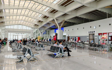 Passengers seated in Noi Bai Airport departure lounge, Hanoi, with visible signage and seating area.