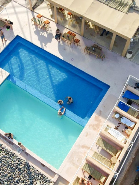 Aerial view of swimming pool at Marrakesh desert camp in Agafay, with sunbathers and loungers.