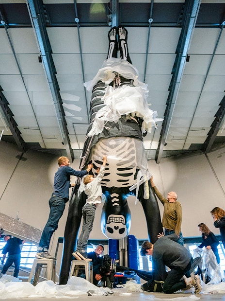 Visitors assembling a large human skeleton model in a museum exhibit.