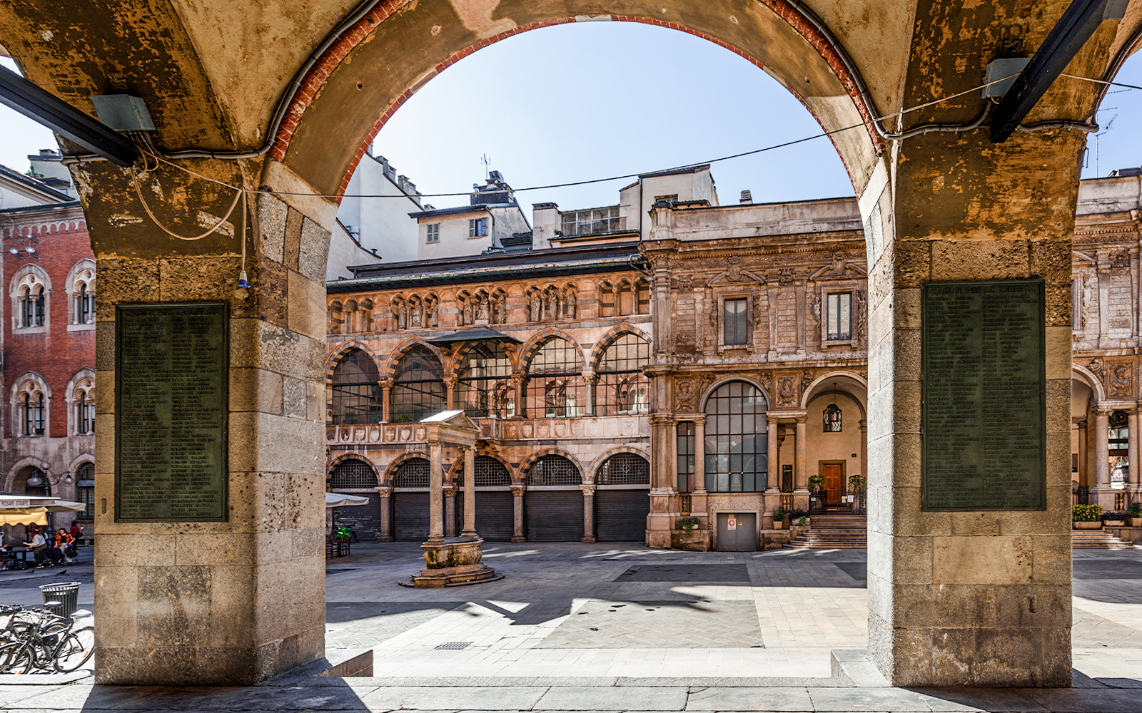 Piazza Mercanti in Milano with historic buildings and tourists exploring the square.