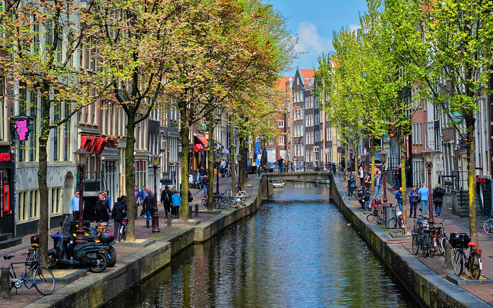 Canal view of Amsterdam's red light district during a cruise, with people walking along the canal.