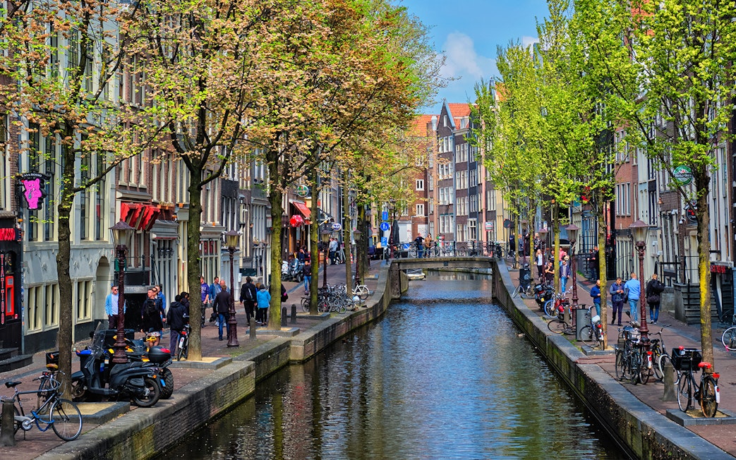 Canal view of Amsterdam's red light district during a cruise, with people walking along the canal.