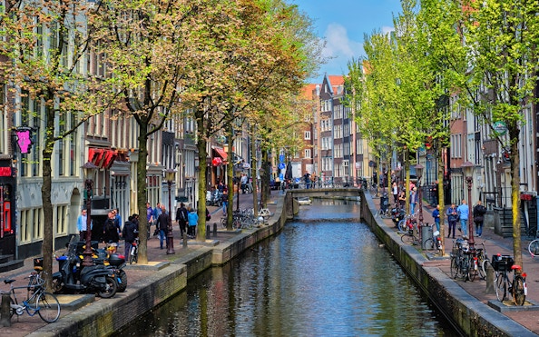 Canal view of Amsterdam's red light district during a cruise, with people walking along the canal.