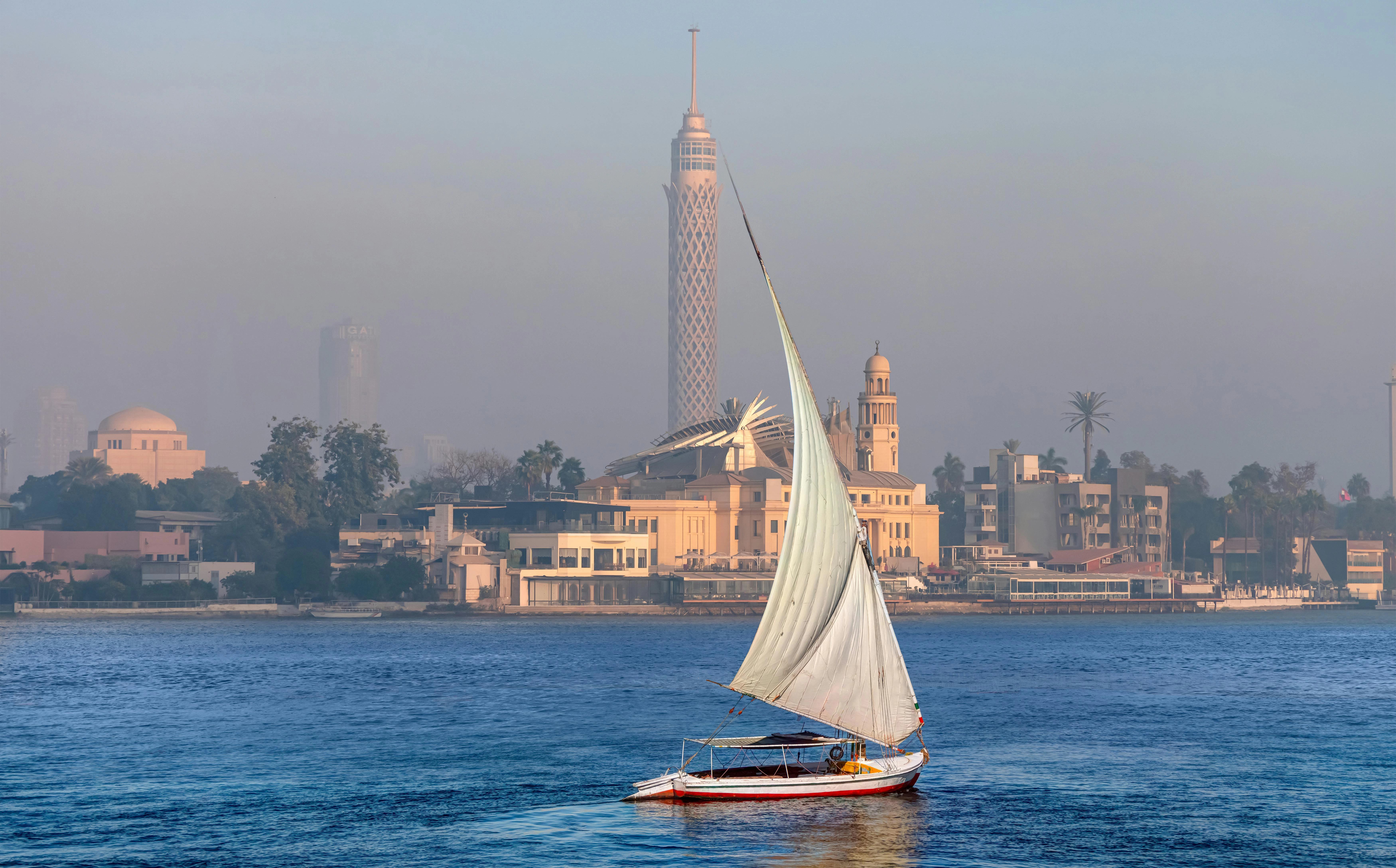 Felucca sailboat on the Nile with Cairo Tower in the background at sunset.
