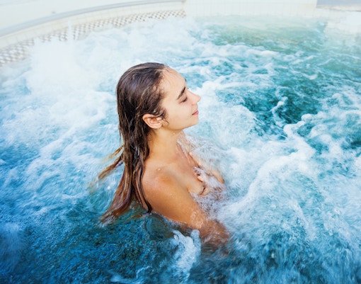 Tourist woman relaxing in a bubbling thermal pool.