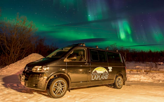 Tour van under Northern Lights in Abisko, Sweden.