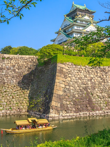 Tourists on a boat in the moat of Osaka Castle, Japan.