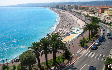 Nice beachfront with promenade and palm trees, part of the Monaco and Nice full-day tour.