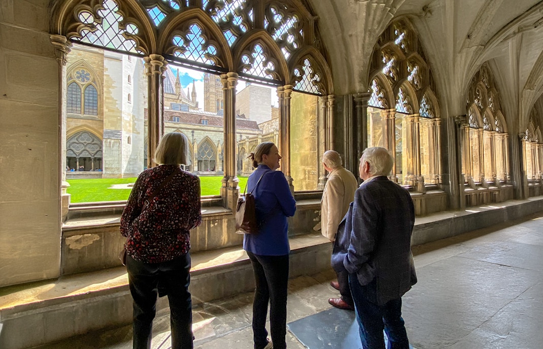 Tourists listening to a guide inside Westminster Abbey, viewing the cloisters.