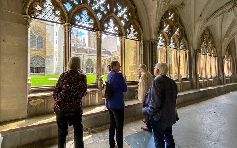 Tourists listening to a guide inside Westminster Abbey, viewing the cloisters.