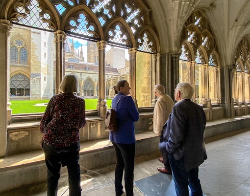 Tourists listening to a guide inside Westminster Abbey, viewing the cloisters.