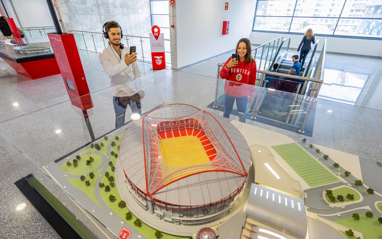 Benfica stadium scale model with visitors taking photos in the exhibit room.