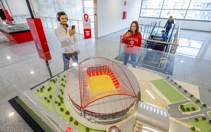 Benfica stadium scale model with visitors taking photos in the exhibit room.