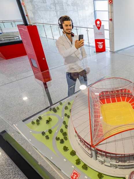 Benfica stadium scale model with visitors taking photos in the exhibit room.